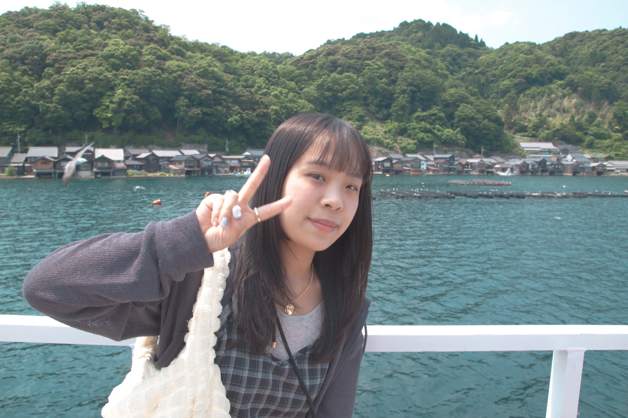 妳在伊根海邊微笑比出勝利手勢